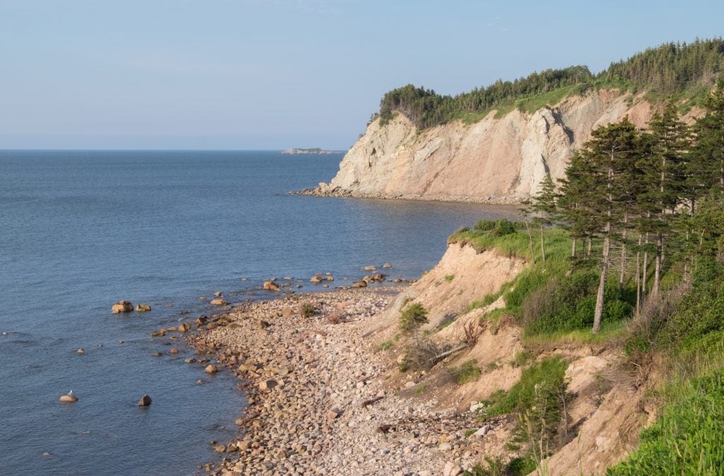 White limestone cliffs topped with grass plunging into the ocean in Cape Breton.