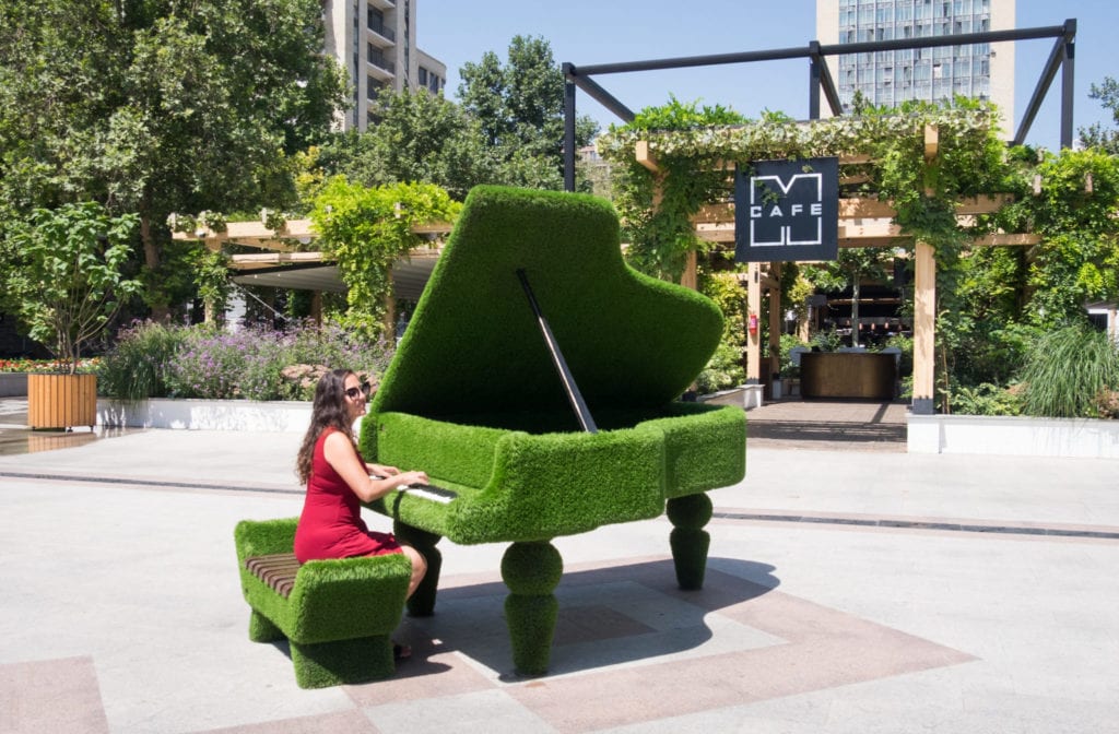 Kate plays a piano made of grass in Yerevan.