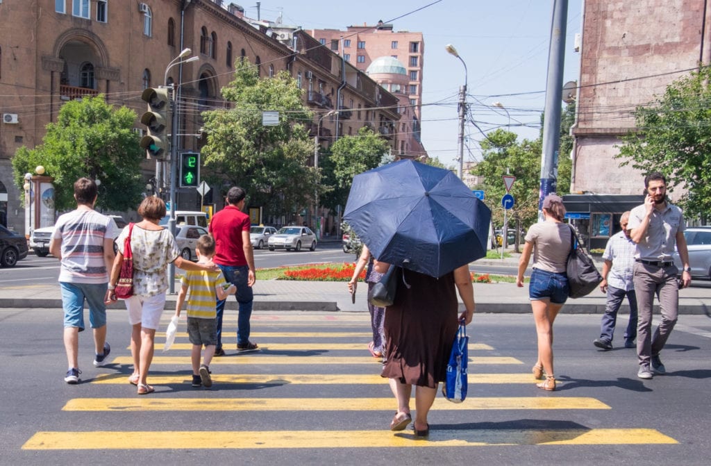 People walking across a yellow crosswalk on a street in Yerevan.