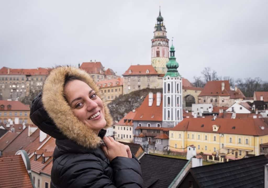 Kate poses in a furry hooded coat in Cesky Krumlov's church tower-topped skyline