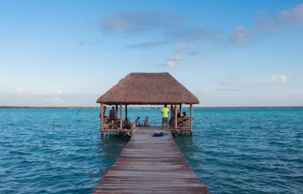 A dock leading to a sitting area with a thatched roof, on Bacalar Lake.