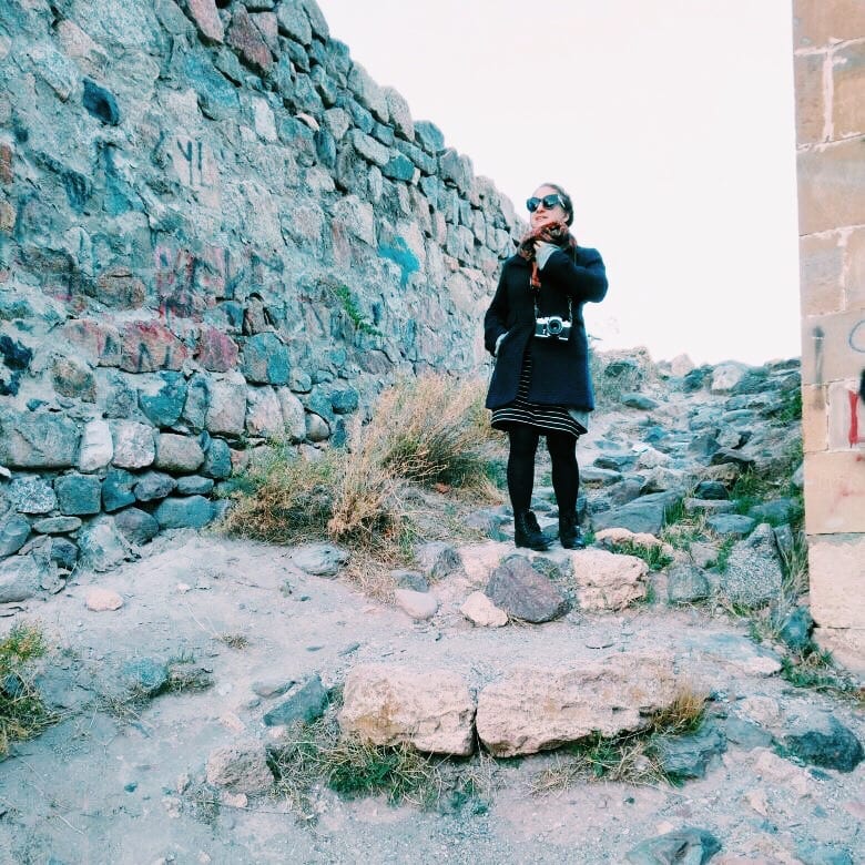 Katie bundled up in a coat and standing on a rocky path in Ani, Turkey.