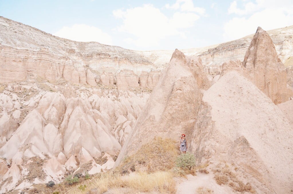 The giant triangle-shaped rocks of Cappadocia, with a tiny Katie next to one for scale.
