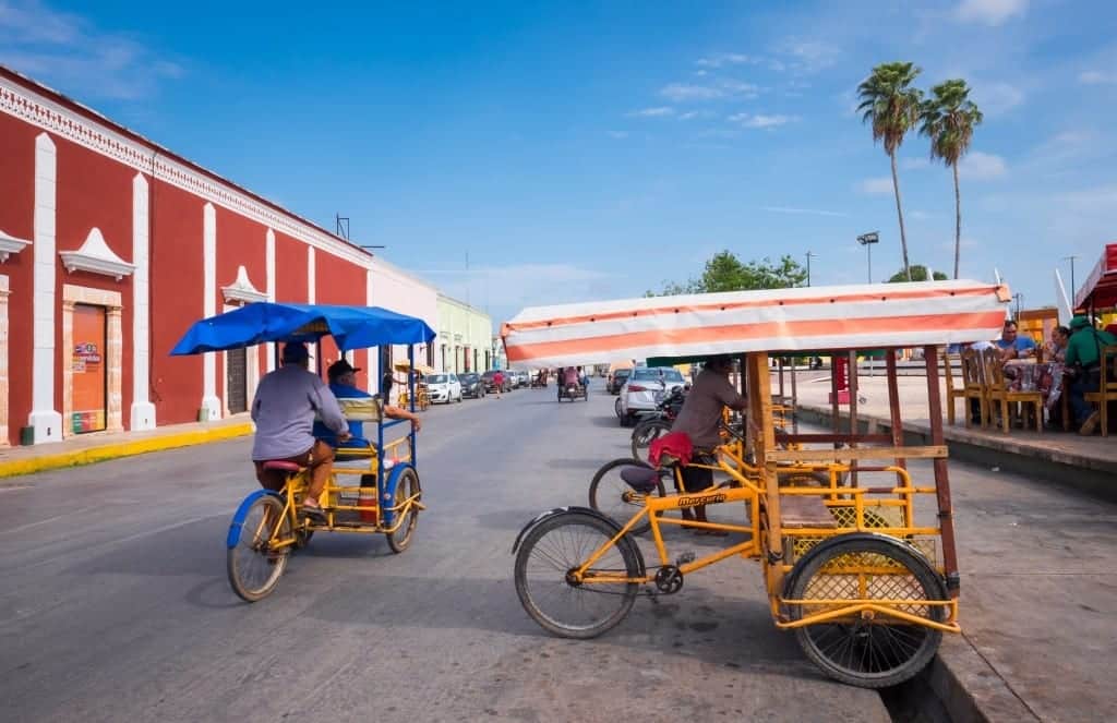 Two pushcarts in front of a red and white colonial building underneath. bright blue sky in Campeche.