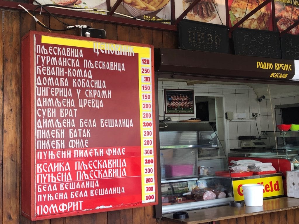 A counter at a takeaway grill with all the menu items written in Cyrillic.