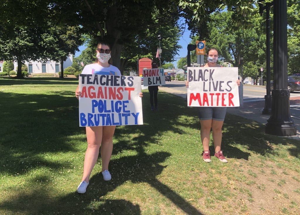 Three women protesting in masks, holding signs that say "Teachers Against Police Brutality" and "Black Lives Matter."