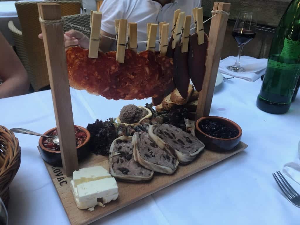 A platter of meats, complete with chorizo-like cured meats hanging from a clothesline on top!