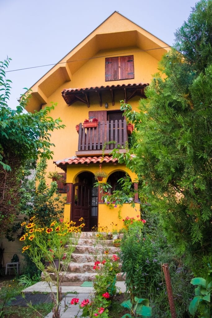 A yellow country house set in a garden full of flowers.