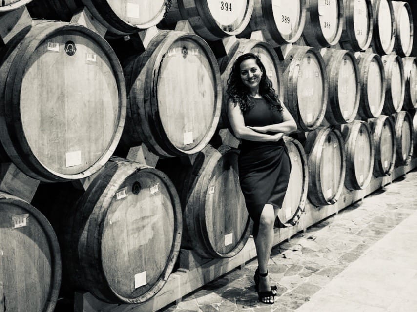 Kate stands in front of wooden bottles filled with brandy at the Ararat Distillery in Yerevan, Armenia.