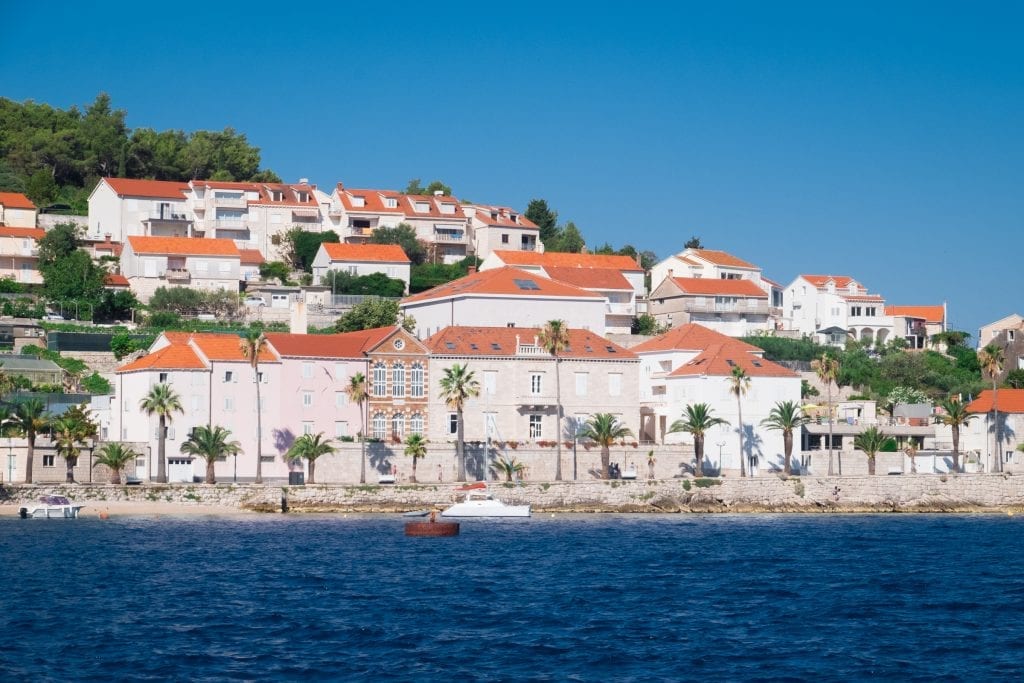 Korcula Town up close: rows of white houses with orange roofs on the edge of the navy blue ocean.