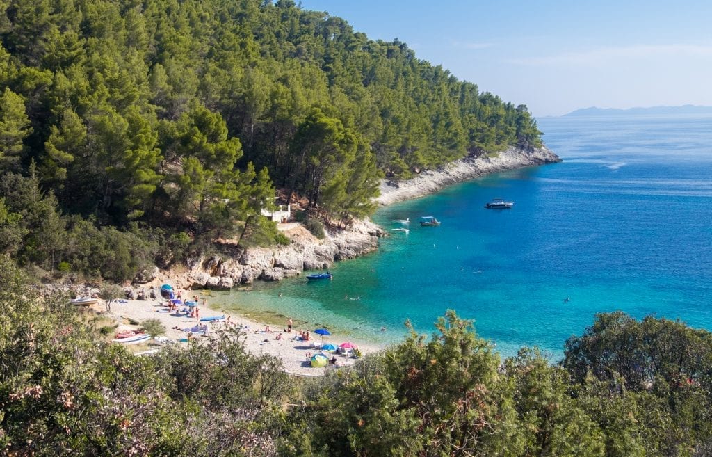 A small white pebble beach leading into the bright blue ocean in Kor?ula, Croatia.