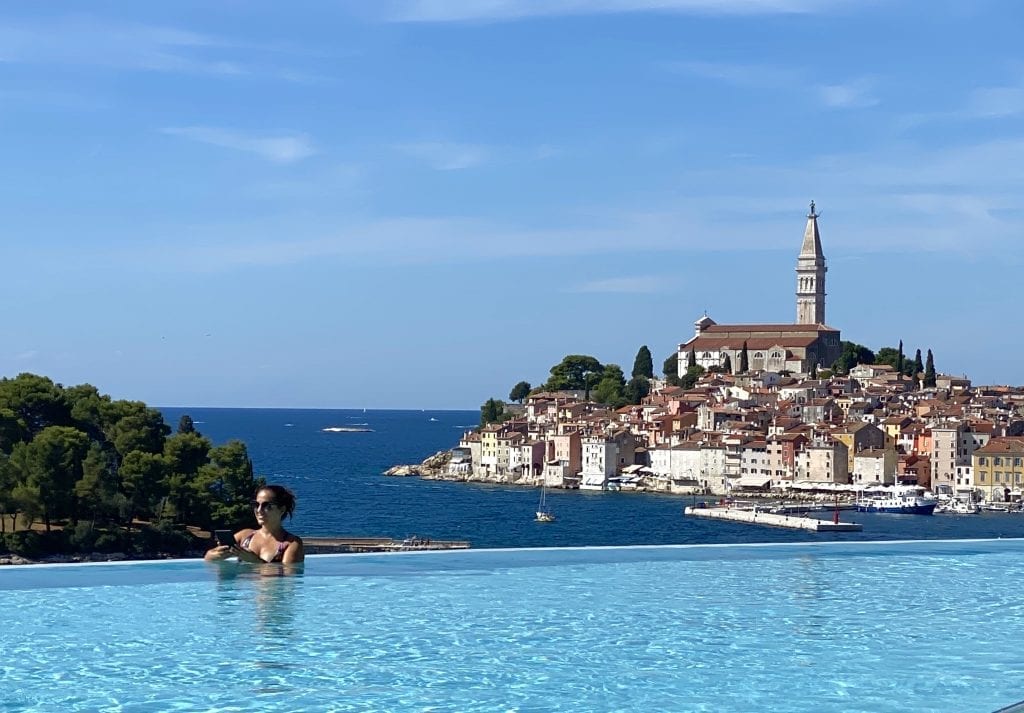 Kate reading her Kindle in an infinity pool overlooking the church-topped city of Rovinj in the distance, at the Grand Park Hotel.