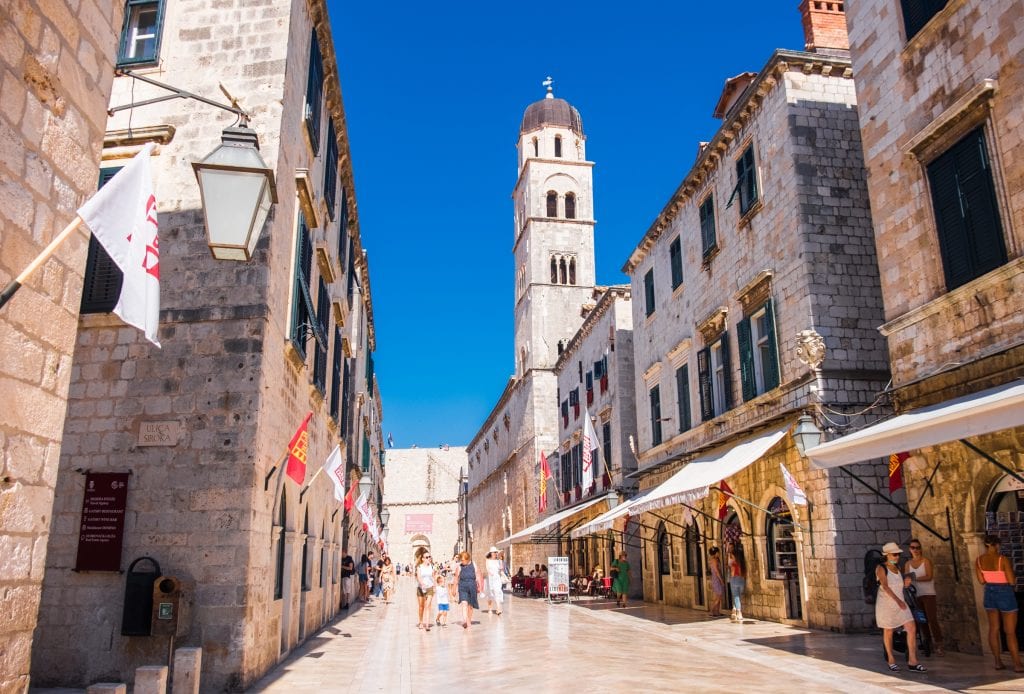 Empty polished streets in the old town of Dubrovnik, underneath a bright blue sky.