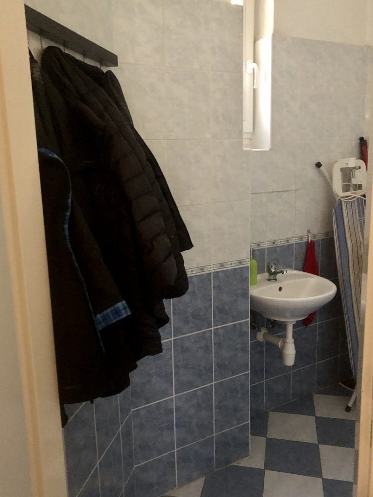 Black jackets hanging on a rack in the bathroom.