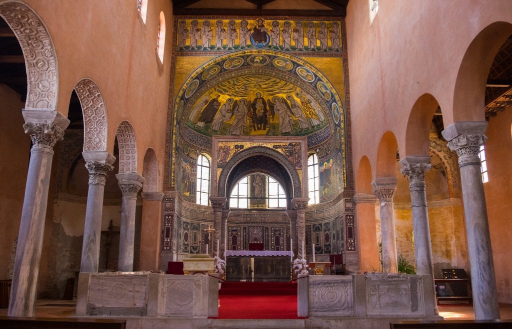 The Euphrasian Basilica of Porec, flanked with columns on each side and a gold Byzantine mosaic above the altar.