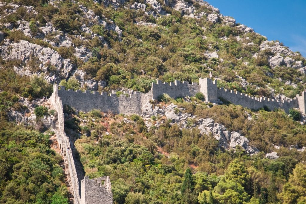 The Ston walls: A gray stone medieval wall running through the green mountains.